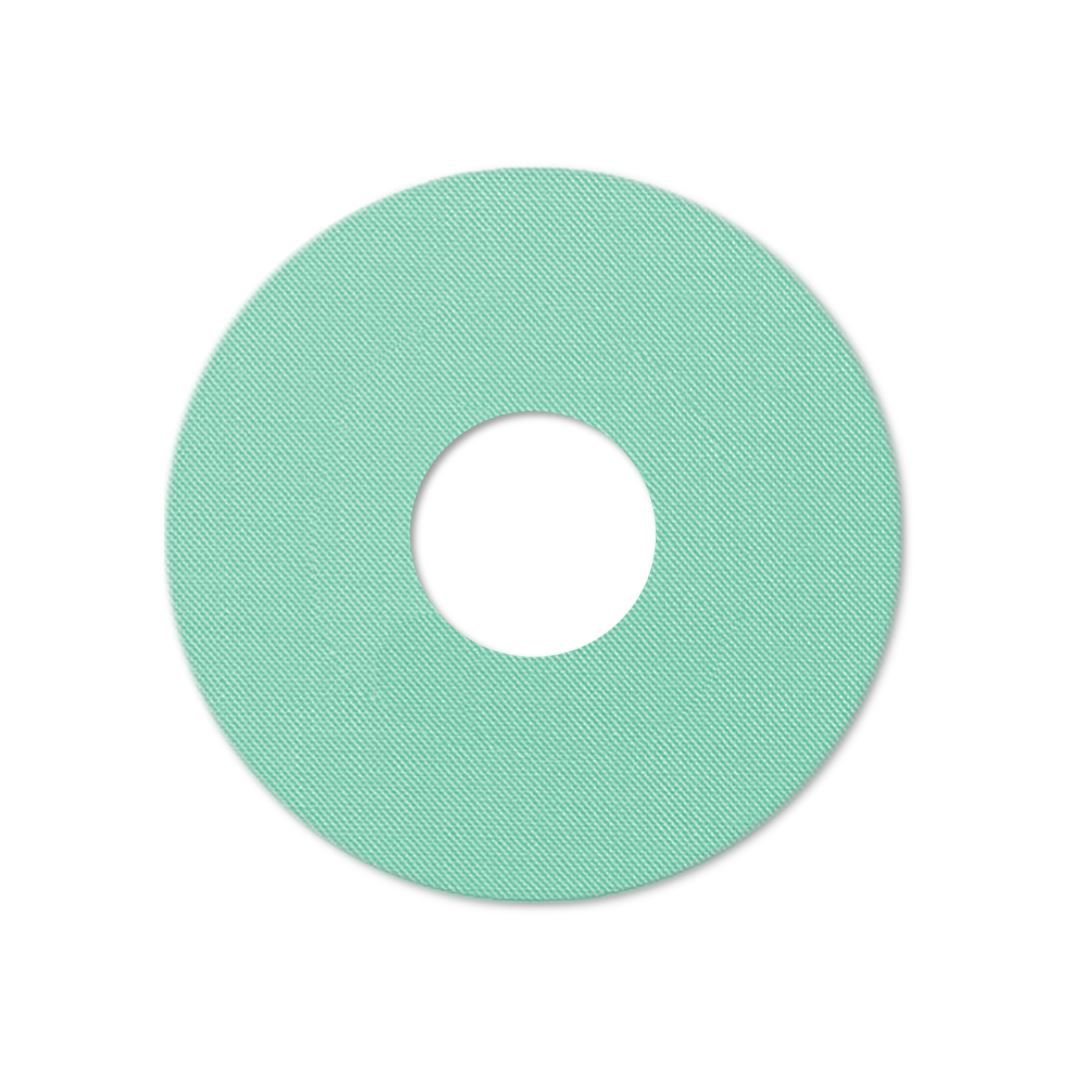 Runder, mintfarbener Katheterpatch mit zentralem Loch. Gewebte Textur.