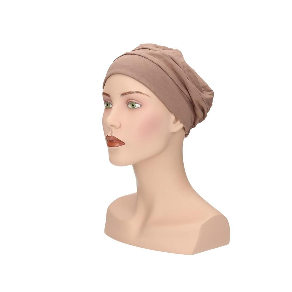 Beigefarbener Turban auf einer Schaufensterpuppe. Seitenansicht. Stoff mit Falten. Elastischer Saum.