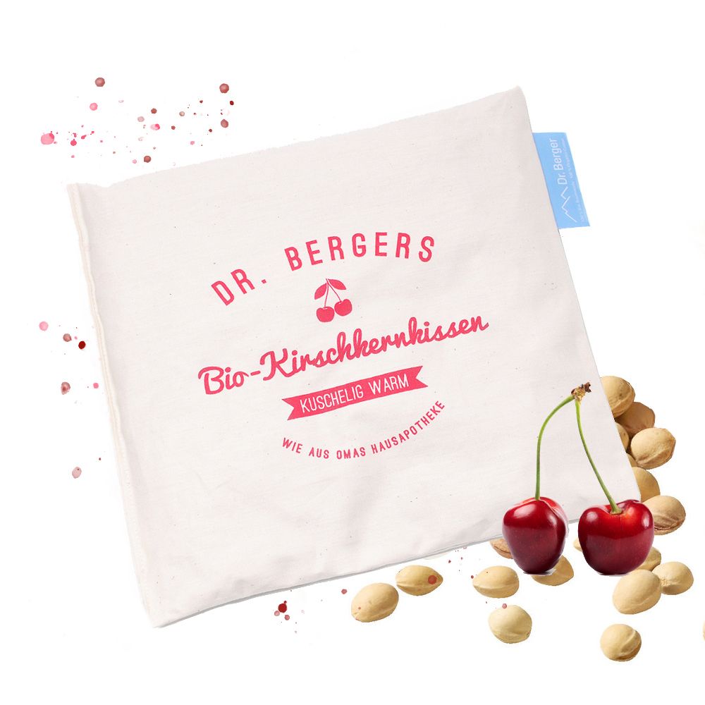 Beiges Kissen mit rotem Schriftzug "Dr. Berger". Kirschen und Kirschkerne daneben. Blaues Etikett.