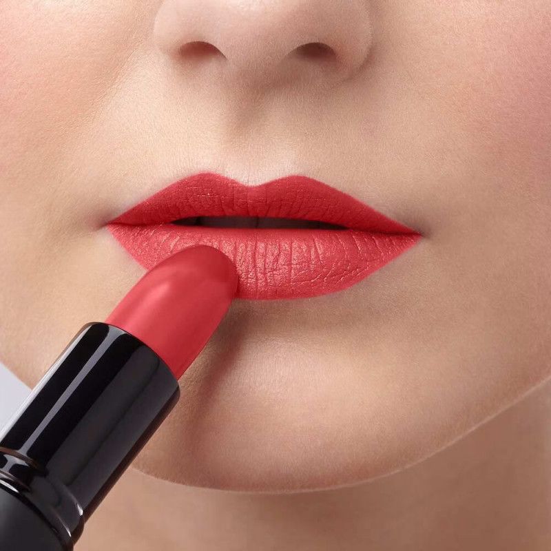 Eine Hand trägt roten Lippenstift auf die Lippen auf.