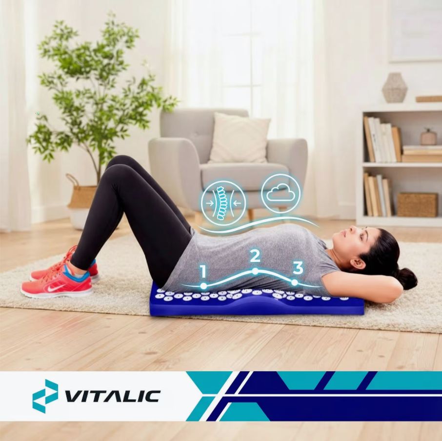 Person liegt auf blauer Akupressurmatte. VITALIC Logo. Umgebung: Teppich, Couch, Pflanze.