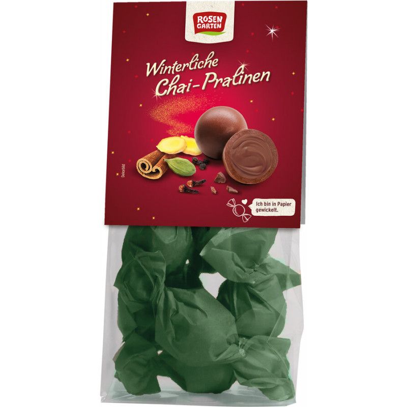 Verpackung mit Pralinen. Roter Hintergrund mit Logo und Schriftzug. Einzelne Pralinen und Gewürze abgebildet. Grüne Papierverpackung.