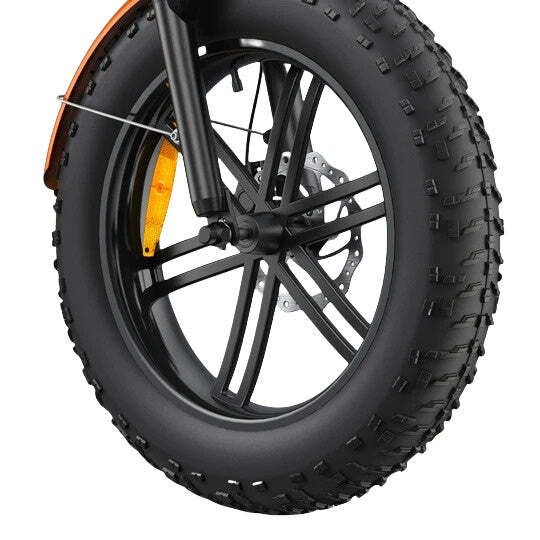 Nahaufnahme eines schwarzen Fahrradreifens. Schwarze Felge mit Speichen, Bremsscheibe und orangefarbenem Schutzblech.