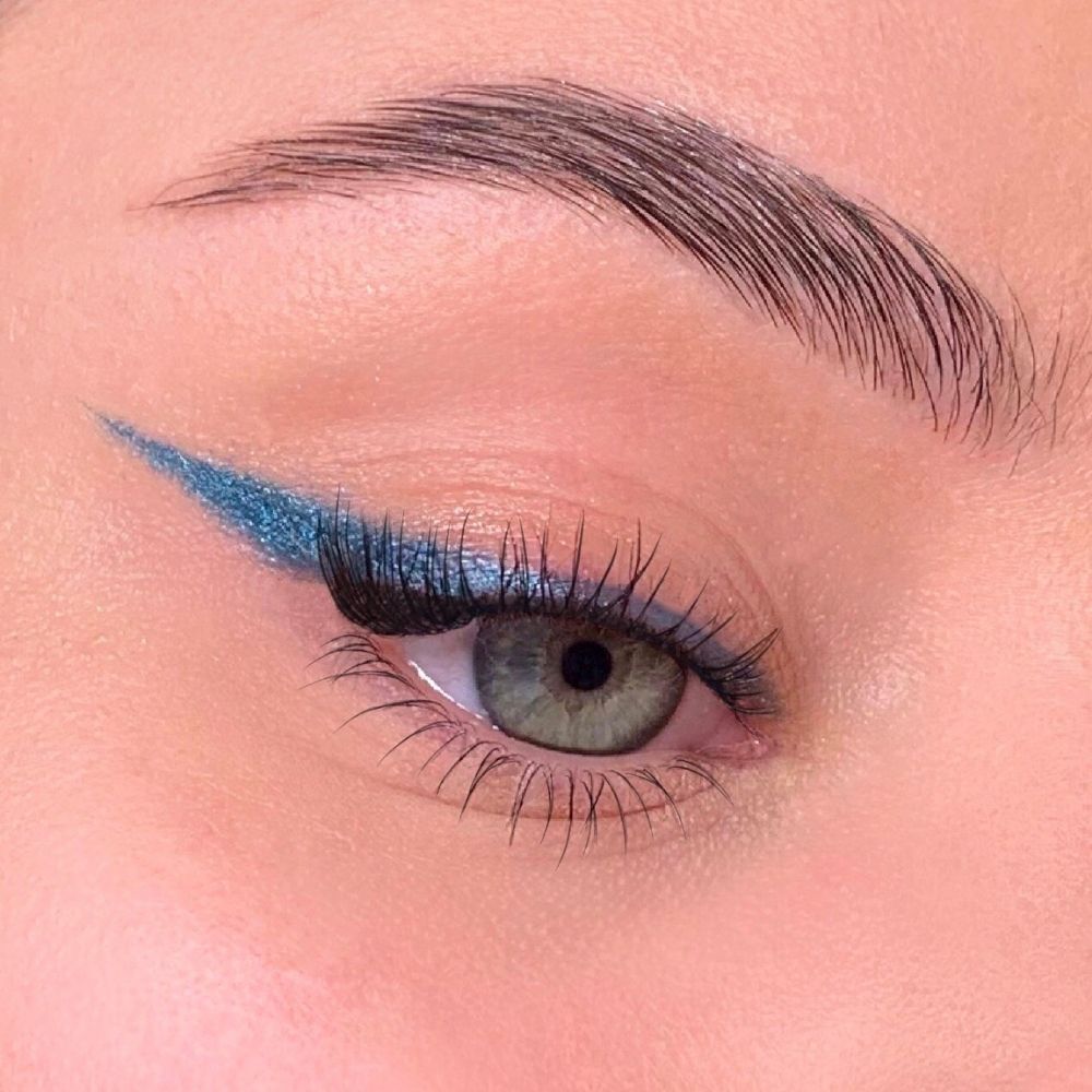 Auge mit blauem Eyeliner. Grünes Auge, blauer Eyeliner-Strich auf dem oberen Lid.
