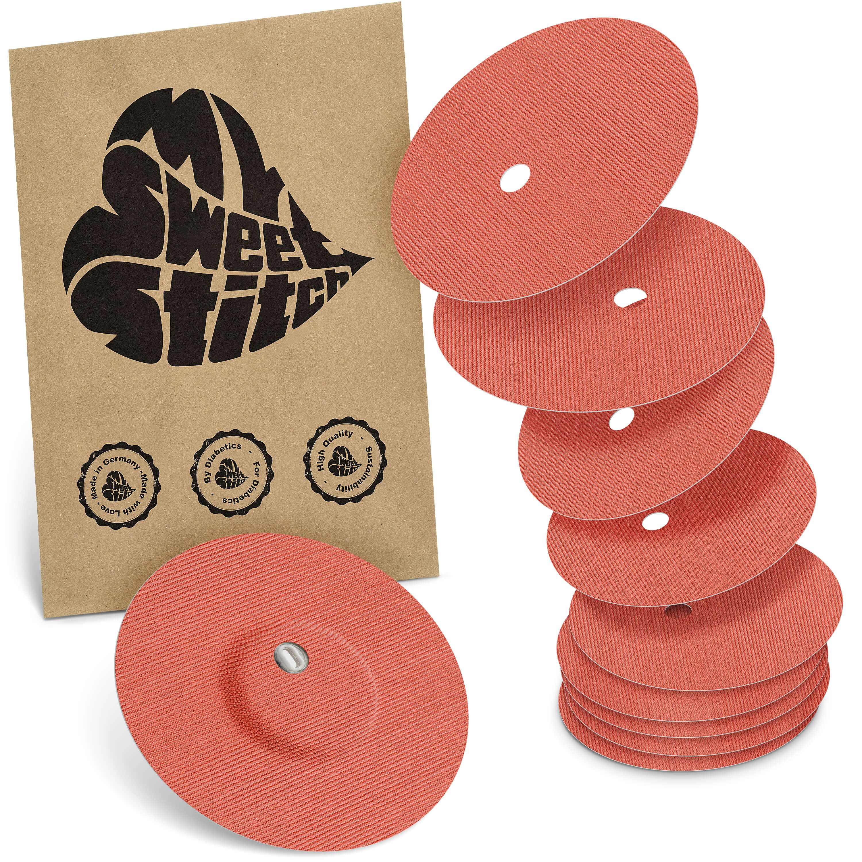 Fixierpflaster mit Belüftungsloch. Mehrere runde, orangefarbene Pflaster mit Loch und brauner Verpackung mit Logo.