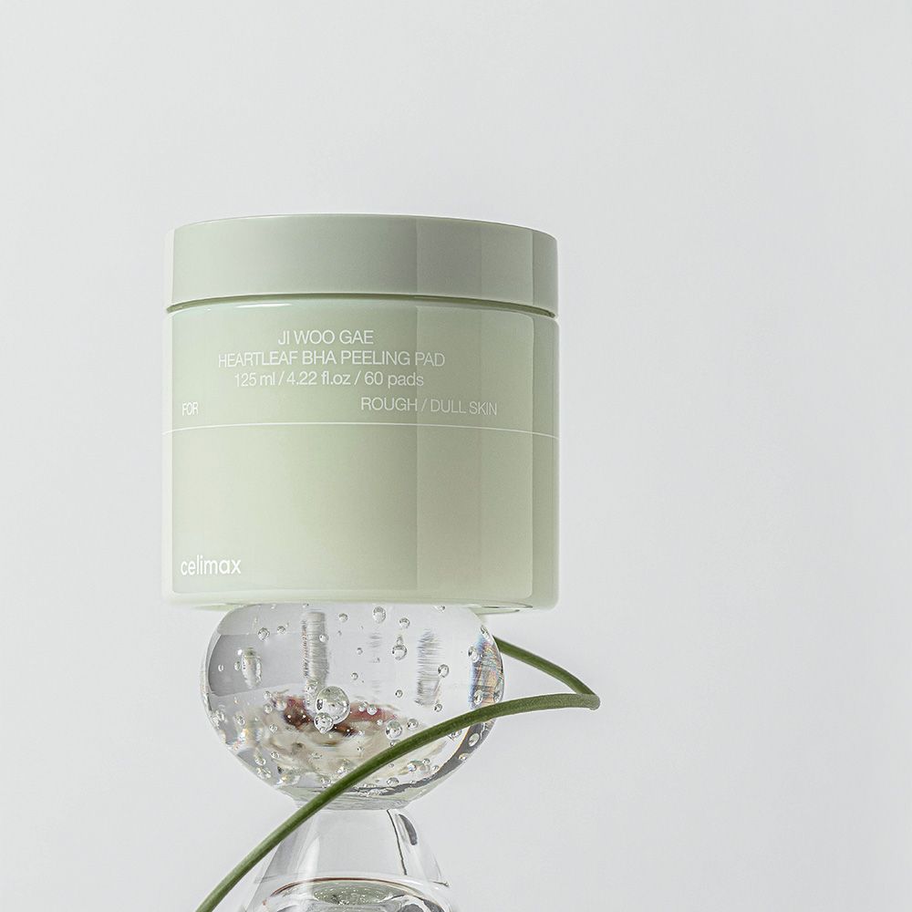 Ein Behälter mit Celimax Heartleaf BHA Peeling Pads, der auf einer Glaskugel steht.