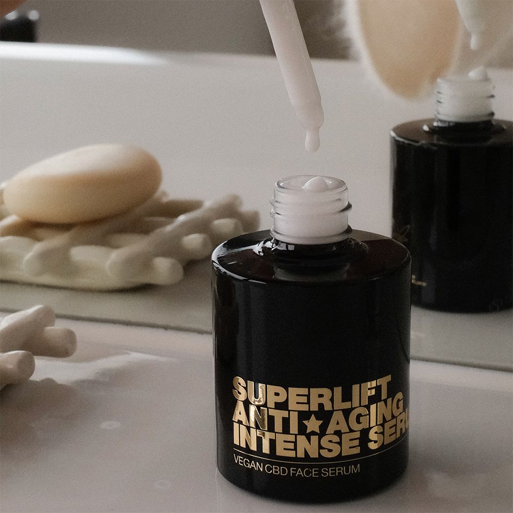Schwarze Flasche mit goldfarbenem Text: Superlift Anti-Aging Intense Serum. Pipette mit Tropfen.