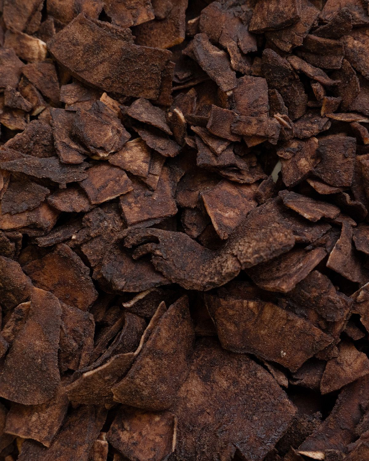 Nahaufnahme von Kokoschips mit Kakao. Dunkelbraune Farbe. Unregelmäßige Form.