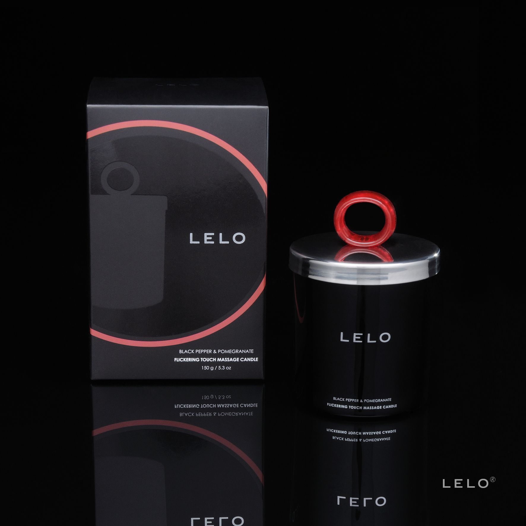 Schwarze Kerze neben schwarzer Verpackung. Roter Kreis auf der Verpackung. "LELO" Schriftzug. "Black Pepper & Pomegranate" Text.