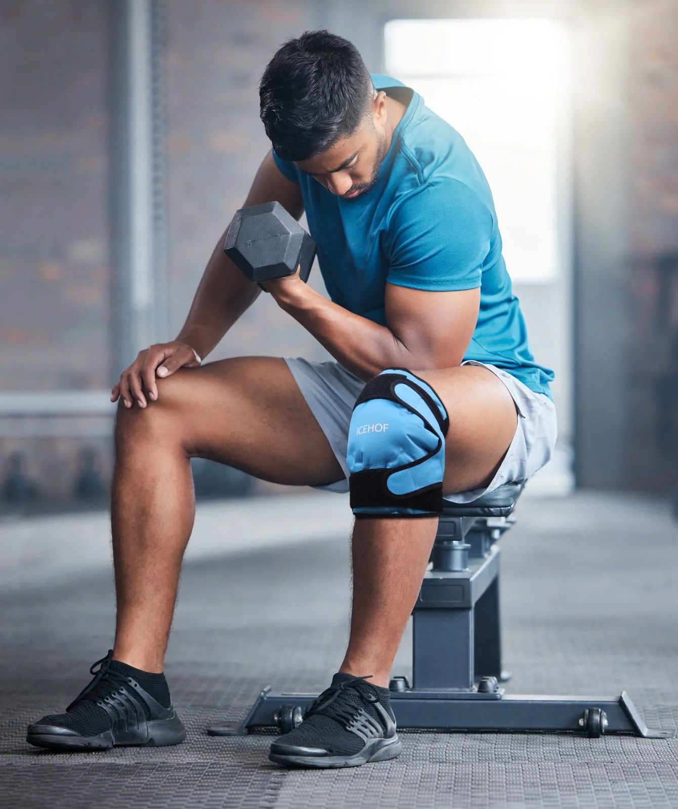 Mann mit blauer Knie-Kühlmanschette hebt Hantel im Fitnessstudio.