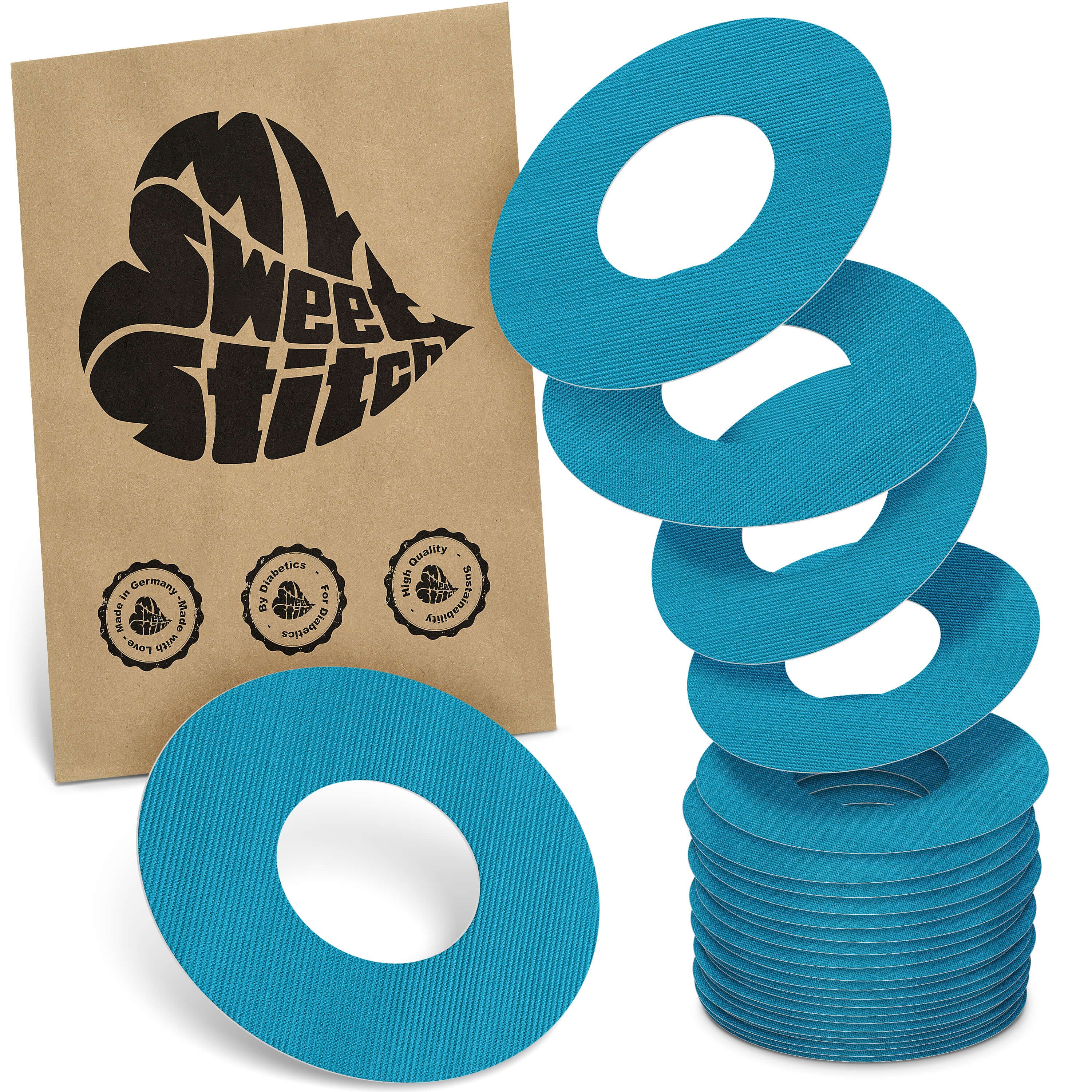 Türkisfarbene Ringpflaster. Neben einer braunen Papiertüte mit Logo liegen mehrere Ringpflaster gestapelt.