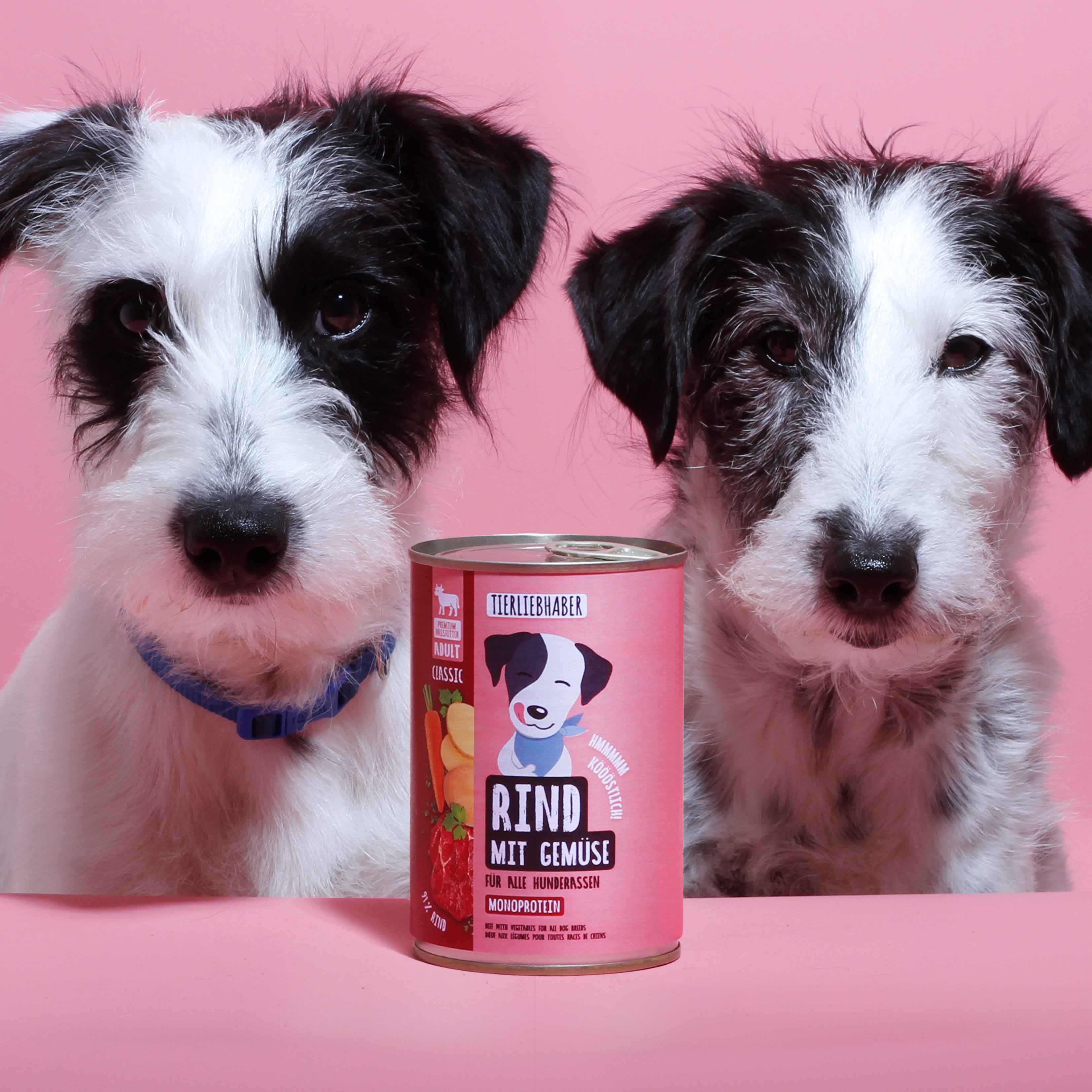 Rosa Dose "Tierliebhaber Rind mit Gemüse" zwischen zwei Hunden.