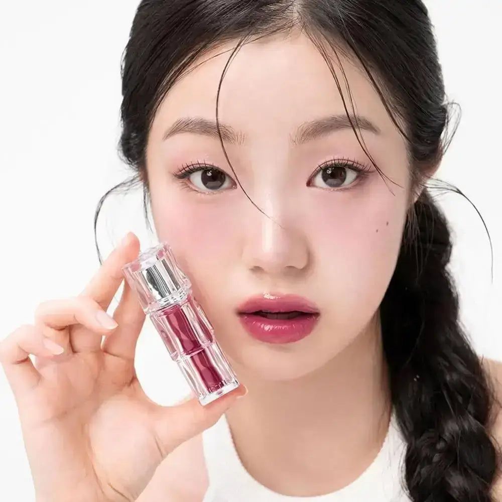 Frau hält einen durchsichtigen Lippenstiftbehälter mit rotem Lippenstift.