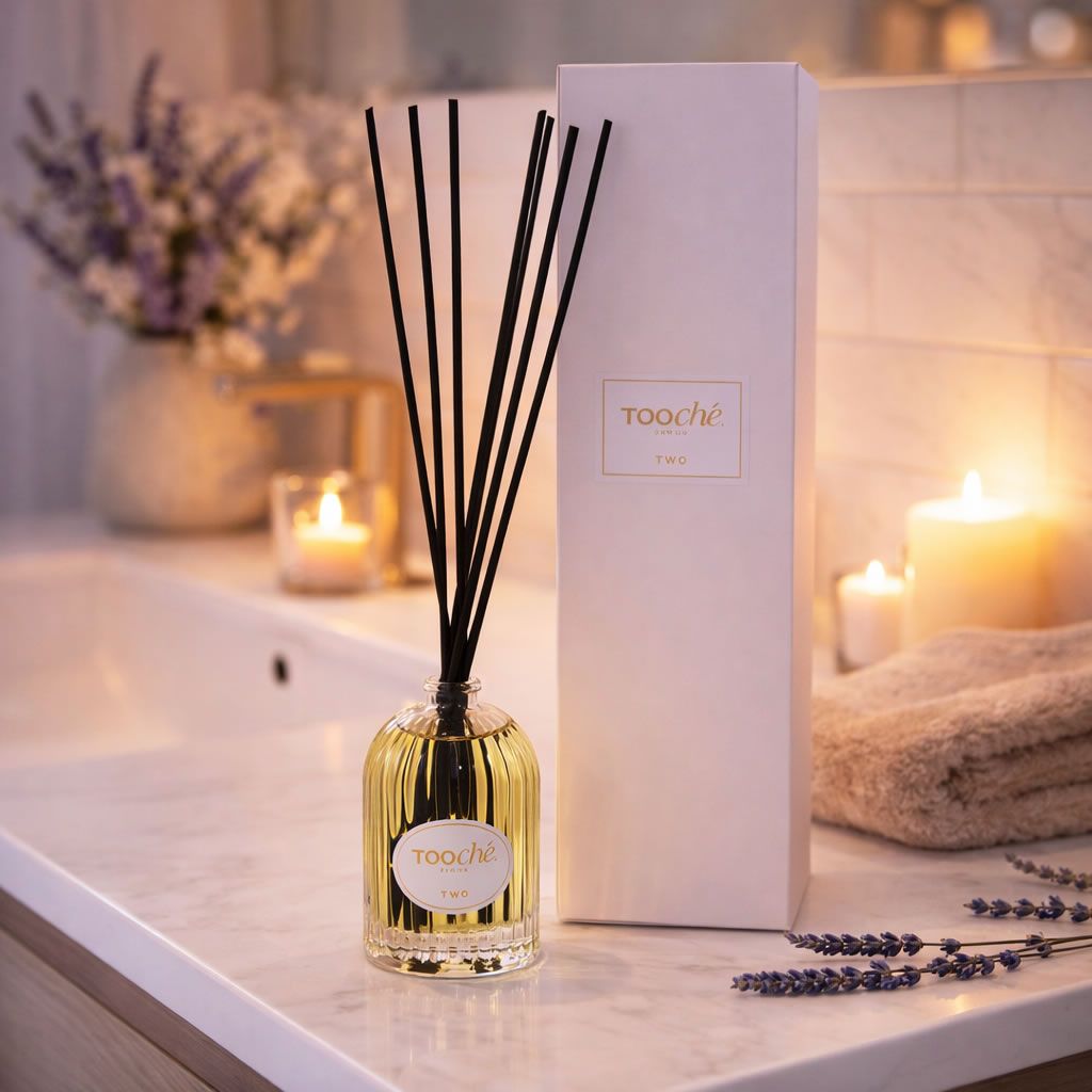 Glasflakon mit schwarzen Stäbchen, neben Verpackung. Aufschrift auf Etikett.