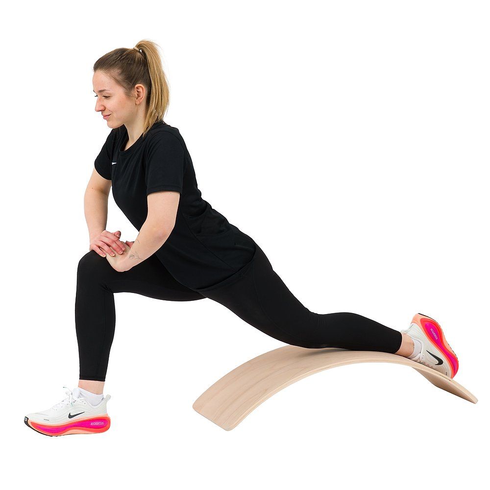 Frau in Ausfallschritt auf einem Balance Board, vorderes Bein gebeugt, hinteres Bein gestreckt.