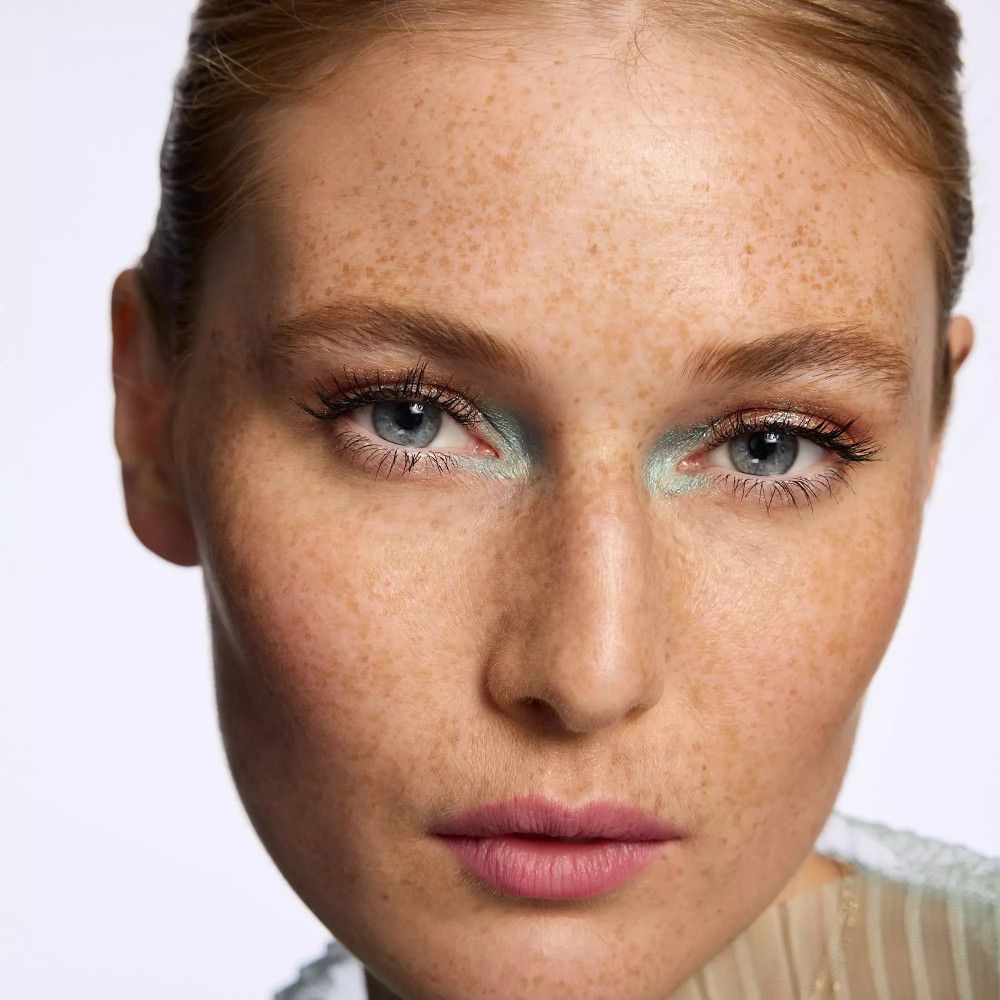 Nahaufnahme einer Frau mit Make-up. Hellblauer Lidschatten. Sommersprossen. Blaue Augen.