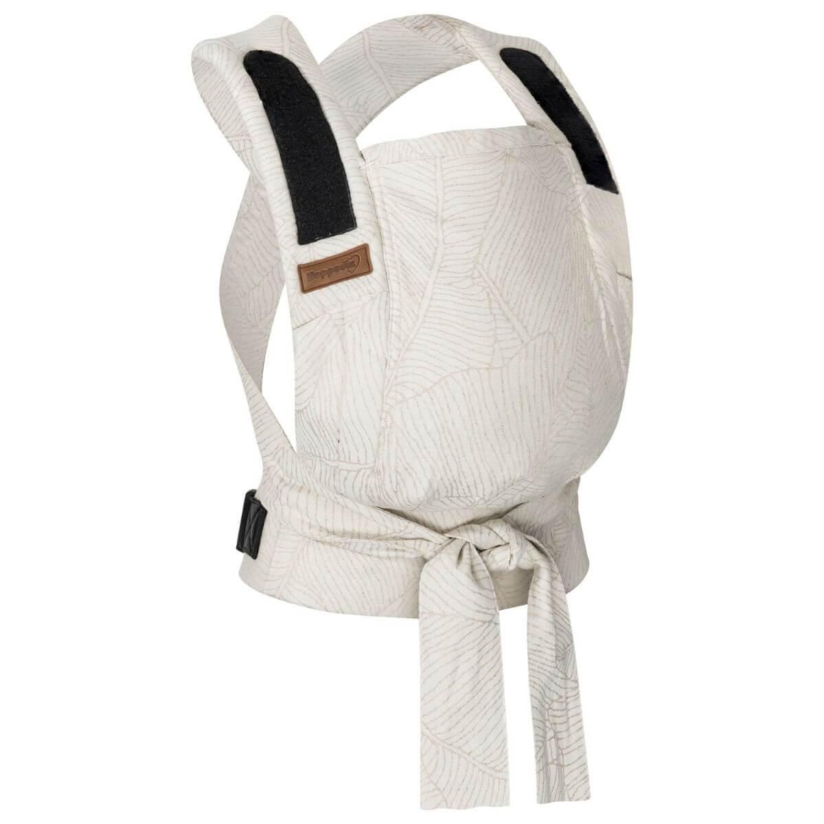 Babytrage mit cremefarbenem Stoff und Blattmuster. Schwarze Schultergurte und Label. Bindeband zum Verschließen.