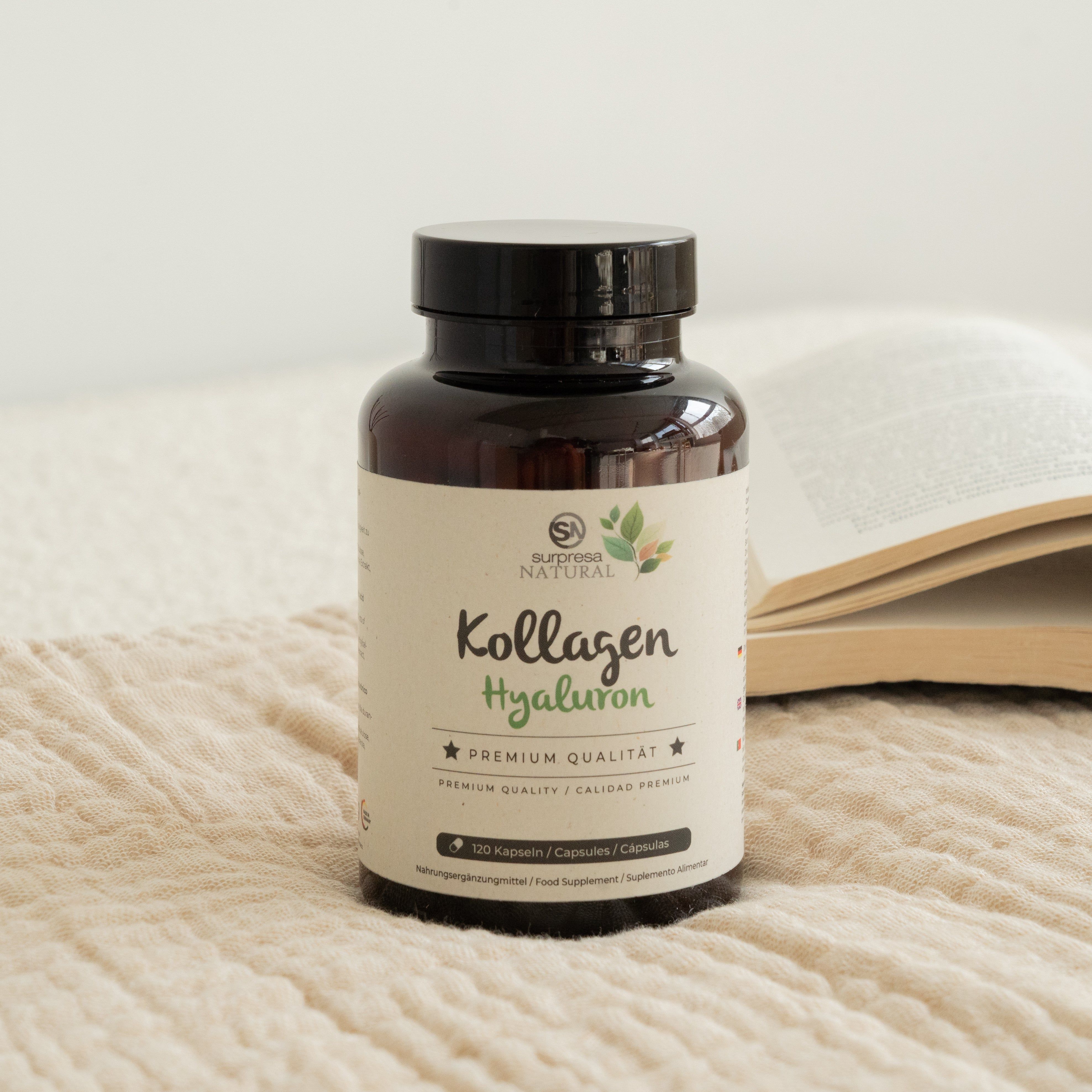 Braune Dose Kollagen + Hyaluron Kapseln, 120 Stück, auf einem Bett mit offenem Buch.
