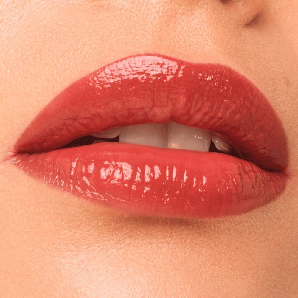 Nahaufnahme von Lippen mit glänzendem Lippen-Make-up. Die Lippen sind rot gefärbt und glänzen.
