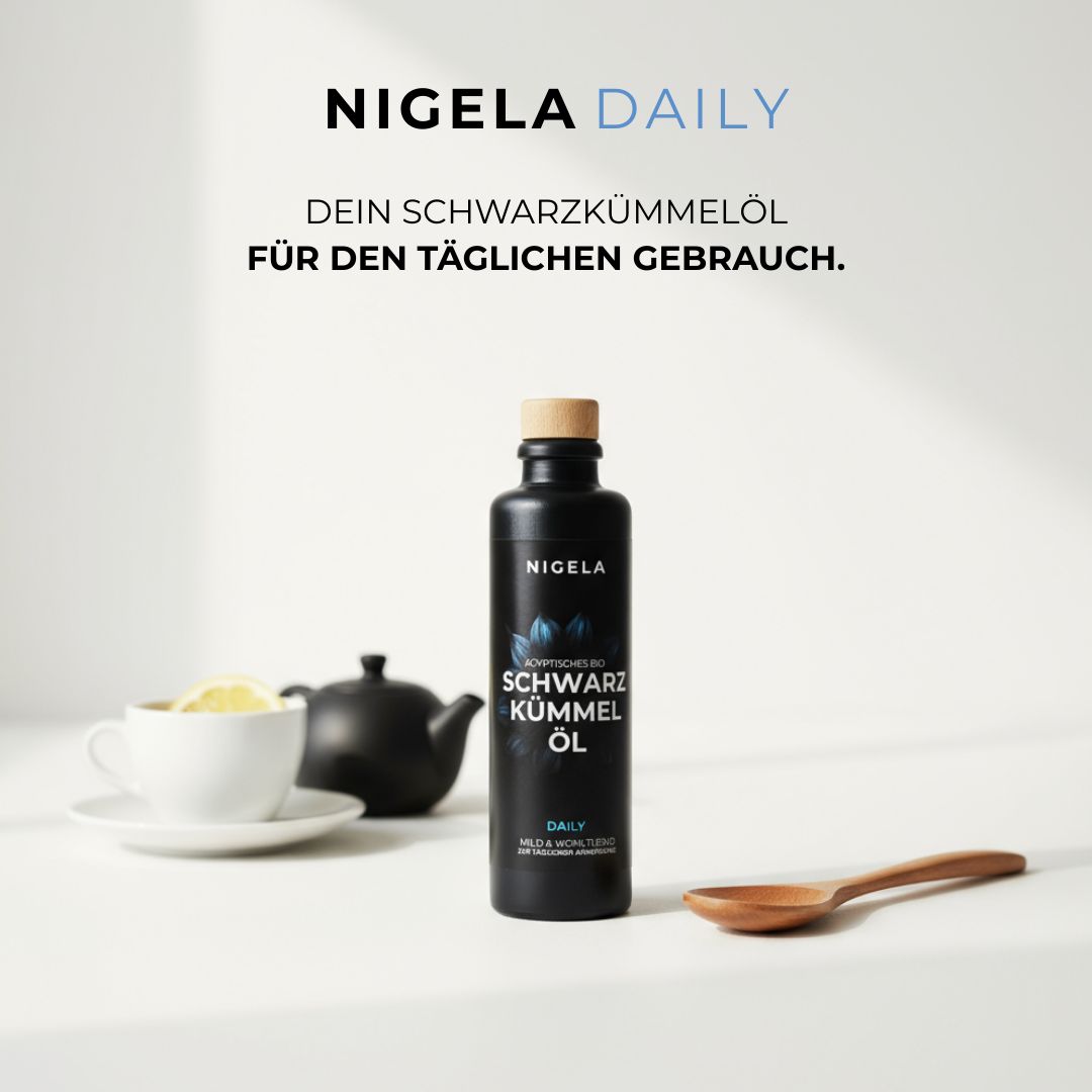 Schwarzkümmelöl-Flasche mit Holzverschluss, neben Teetasse und Löffel. Text: Nigela Daily, Ägyptisches Schwarzkümmel Öl.