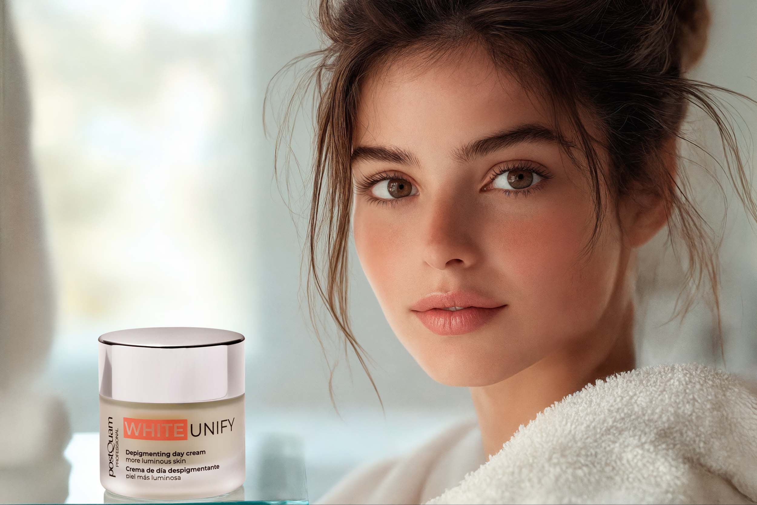 Frau mit Creme-Tiegel. Aufschrift WHITE UNIFY, Depigmenting day cream, mehr leuchtende Haut. Marke Postquam. Produkt neben Frau.