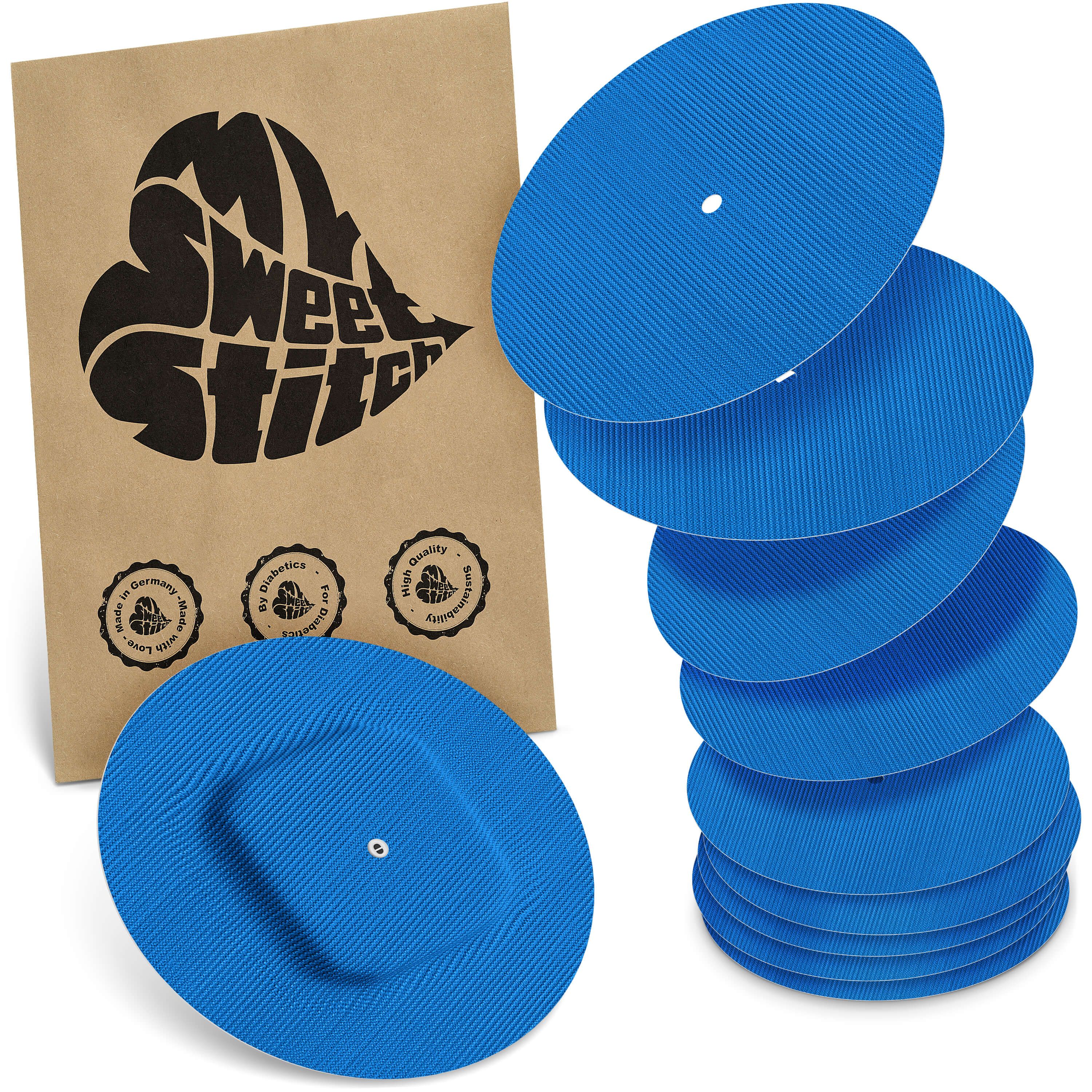 Blaue, runde Pflaster mit geriffelter Oberfläche. Neben einer braunen Verpackung mit Logo. Einige Pflaster sind gestapelt.