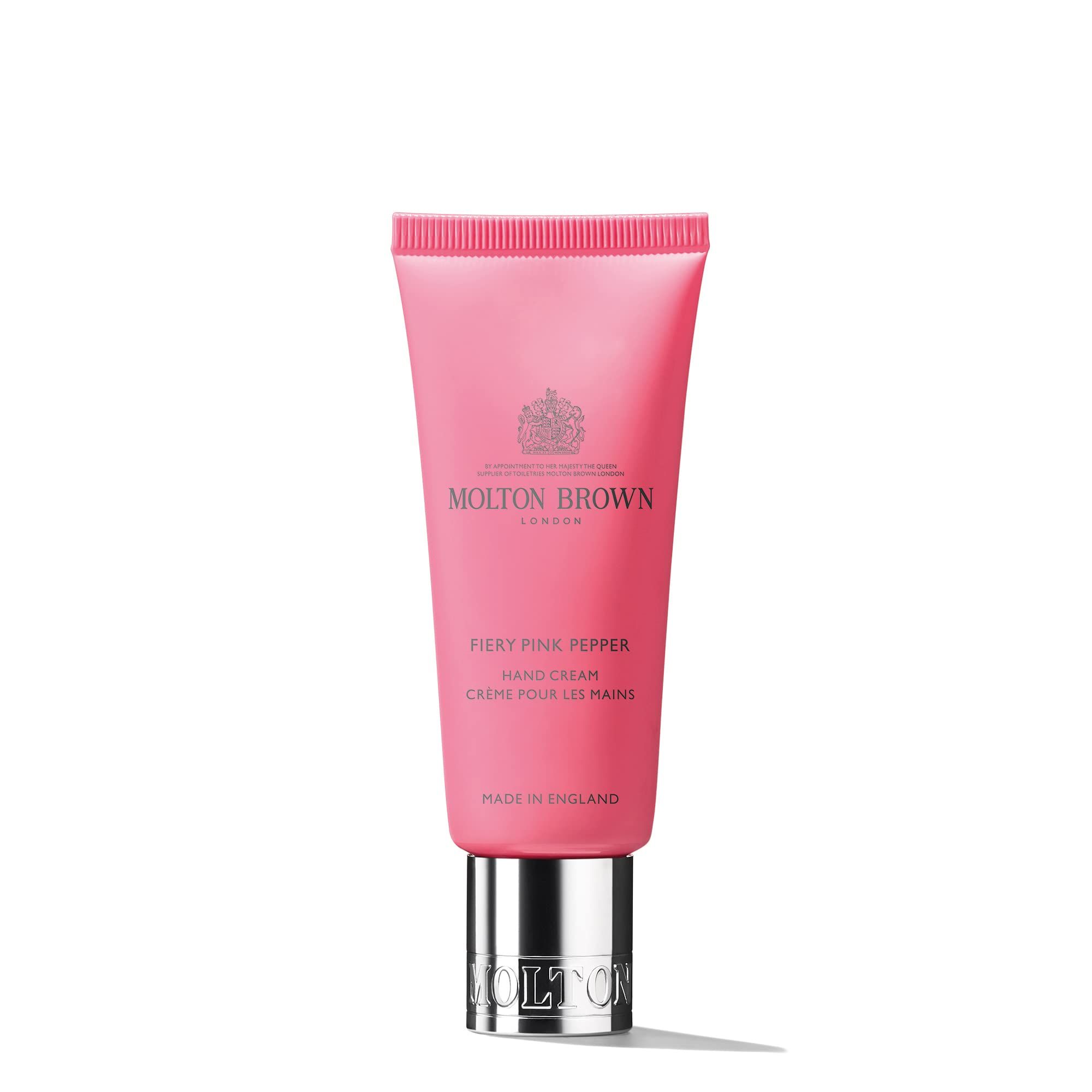 Produktarrangement. Rosa Handcreme-Tube, Flasche, Zerstäuber, Seifenspender, Feuerzeug, rote Beeren.