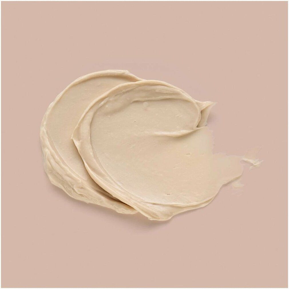 Helle, cremefarbene Paste auf rosa Hintergrund. Zwei cremige Streifen, Textur sichtbar.