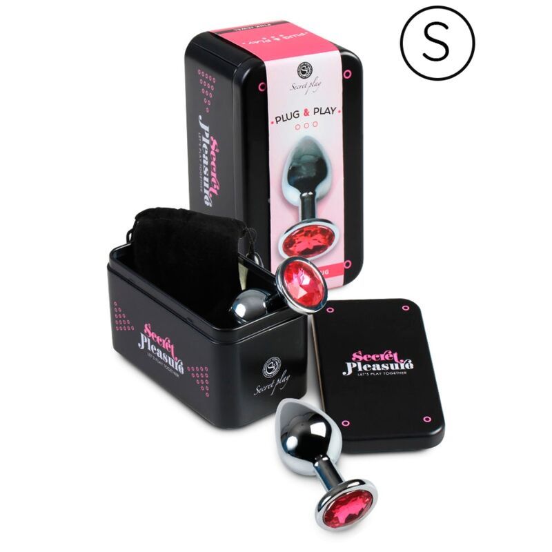 Produkt-Set: Metall-Analplug, Dose, Beutel, Karte. Plug mit rosa Kristall. Dose mit Logo und Schriftzug 'Secret Pleasure'.