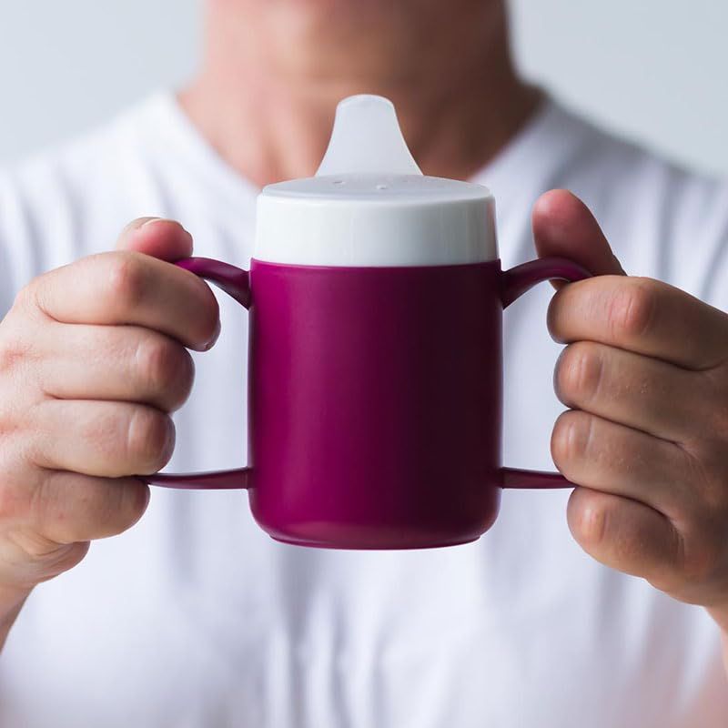 Person hält einen lila Becher mit zwei Henkeln und Trinkaufsatz.