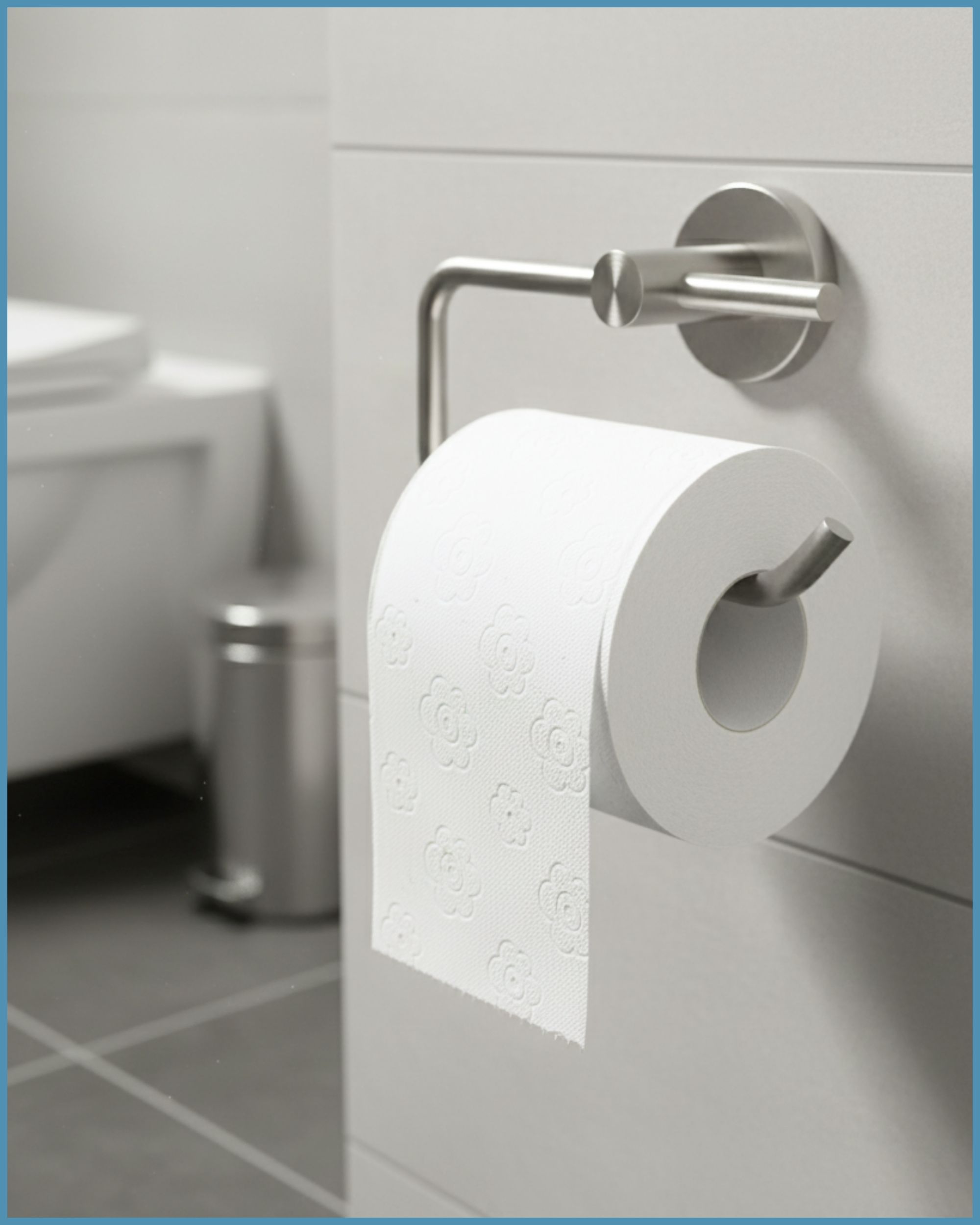Toilettenpapierrolle in Halterung. Weißes Papier mit floralem Muster. Halterung aus Metall, an weißer Wand.
