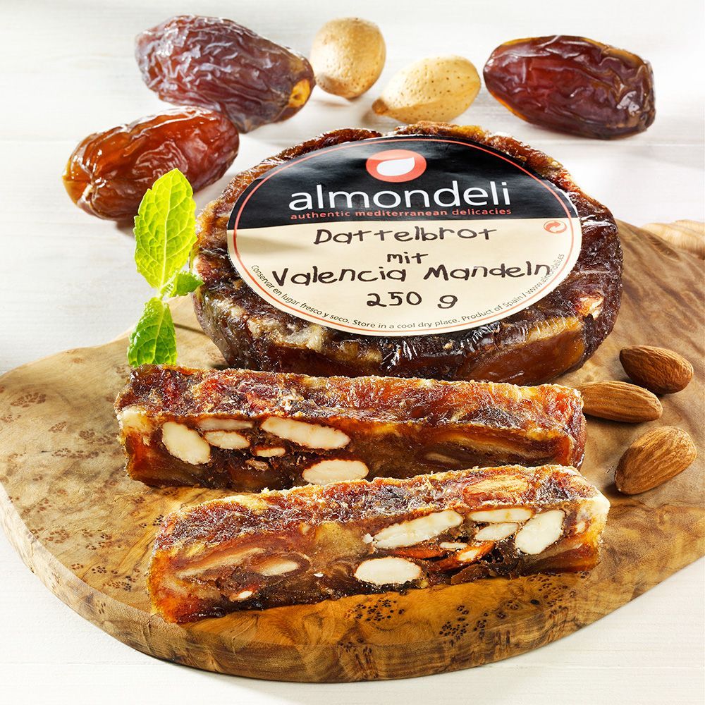 Dattelbrot mit Valencia Mandeln, geschnitten, auf Holzbrett. Aufschrift: almondeli, Dattelbrot mit Valencia Mandeln, 250 g.