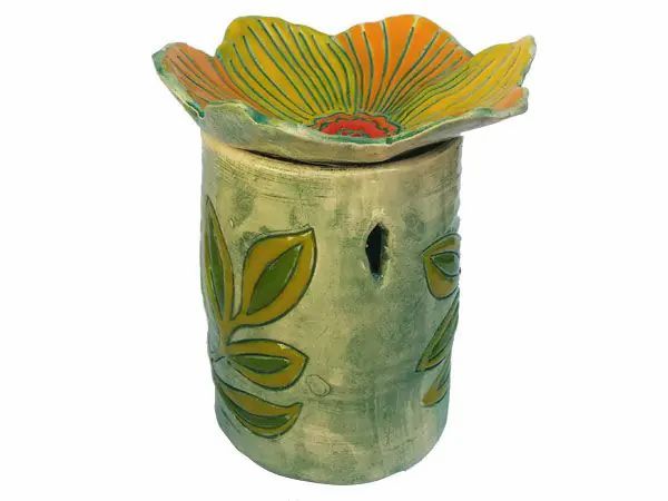 Duftlampe mit gelber Blütenform. Zylindrischer Körper mit Blattmuster. Oben eine gelb-orange Blüte. Loch für Teelicht.