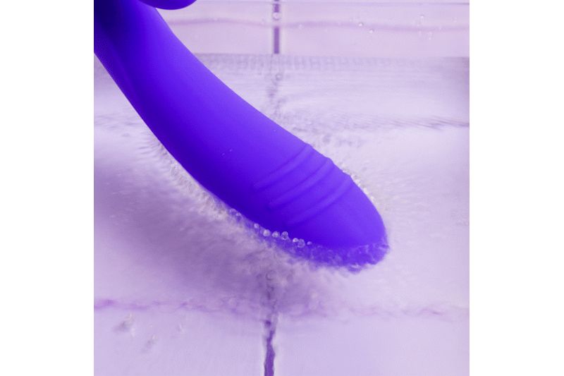 Vibrateur violet sous l'eau. Le vibrateur a une surface rainurée.