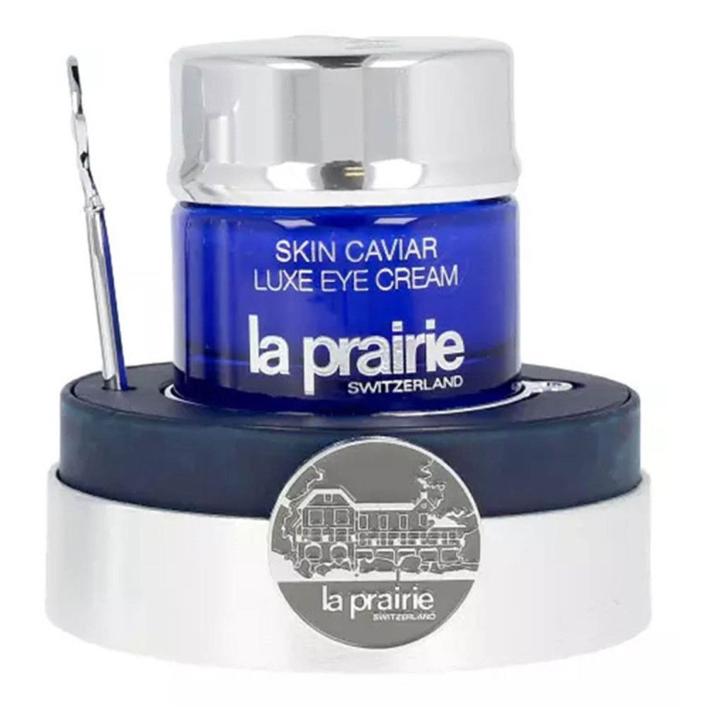 Blaues Glas mit silbernem Deckel, Spatel und Sockel. Aufschrift: Skin Caviar Luxe Eye Cream, La Prairie, Switzerland.