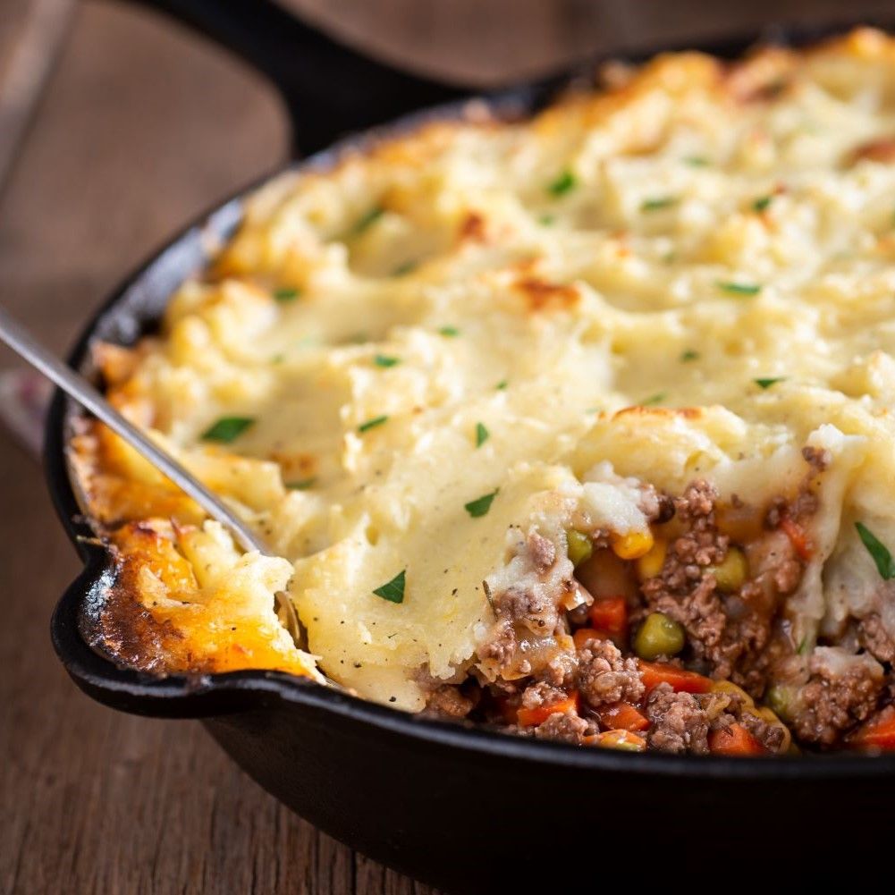 Nahaufnahme von Shepherd's Pie in einer schwarzen Pfanne. Obenauf Kartoffelpüree, darunter Hackfleisch und Gemüse.