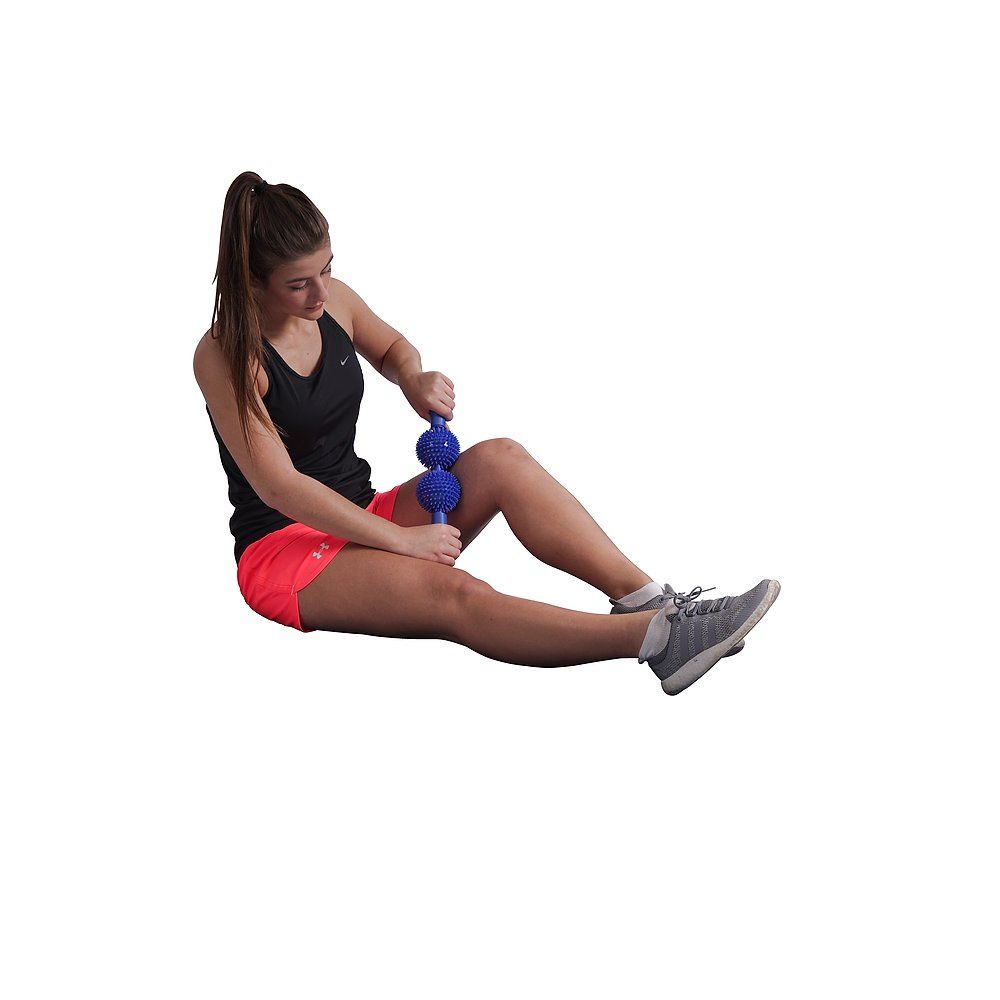 Frau sitzt und massiert Oberschenkel mit blauem Massagestab. Sportkleidung. Weißer Hintergrund.