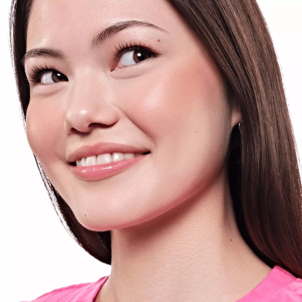 Porträt einer Frau mit gebräunter Haut. Sie trägt rosa Kleidung. Rouge auf den Wangen.