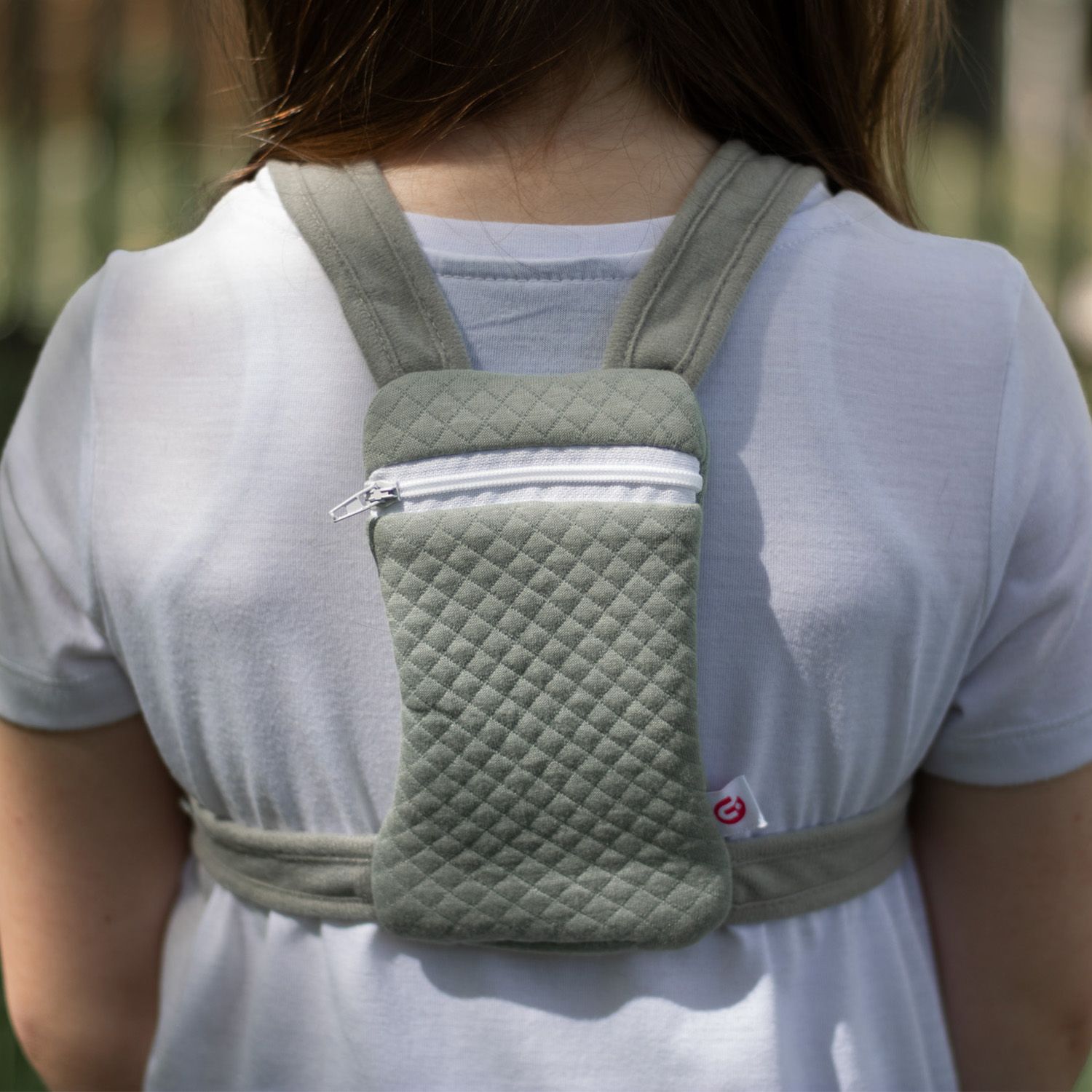 Rückansicht einer Person mit grünem Rucksack. Reißverschlussfach mittig, gestepptes Muster.