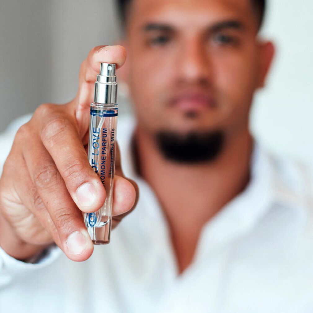 Mann hält einen Flakon. Aufschrift: Eye of Love, Pheromone Parfum, Unscented Male. Silberner Sprühkopf.