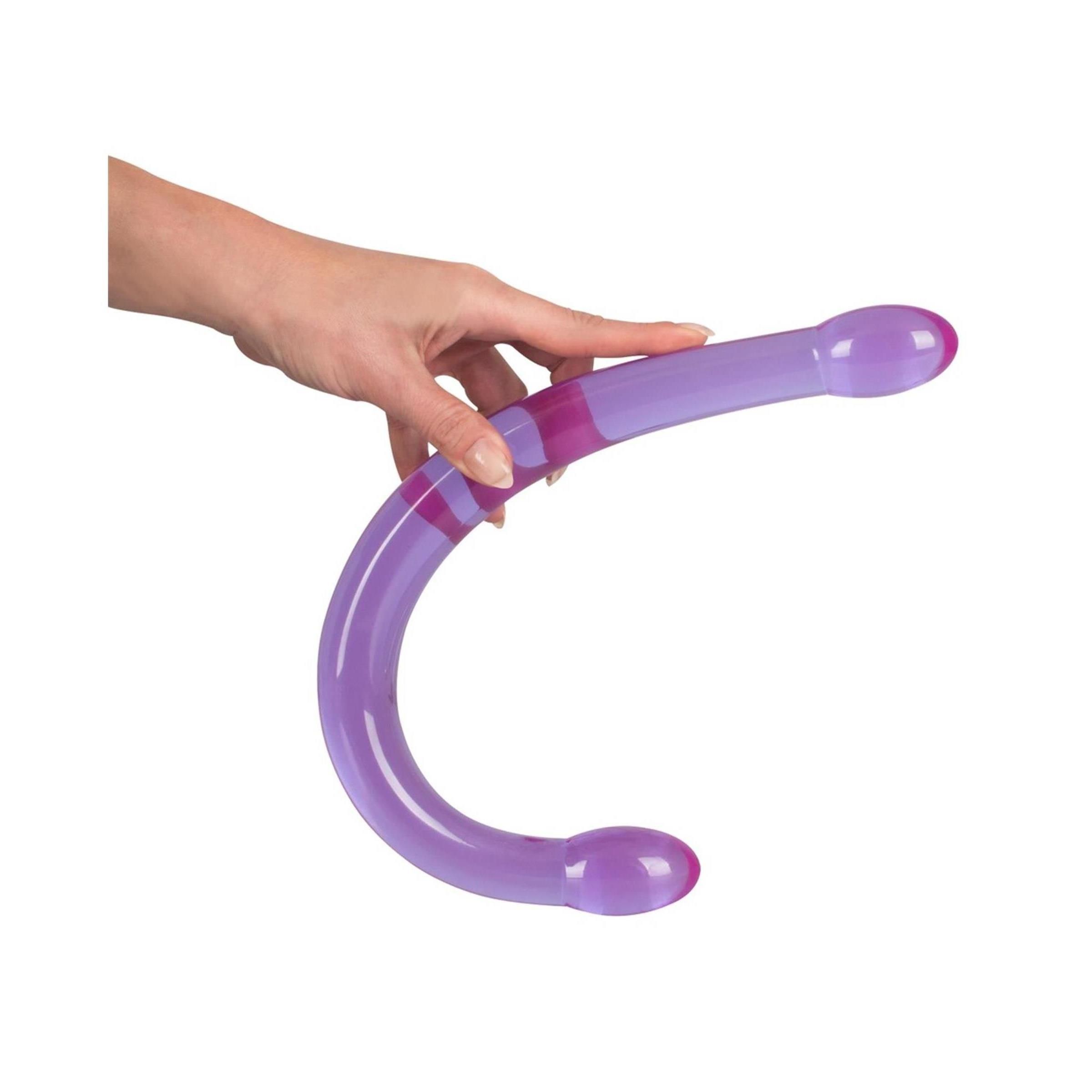 Lila Wellness-Produkt mit zwei abgerundeten Enden. Gehalten in einer Hand.