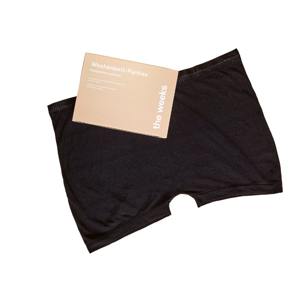 Schwarze Netzhose mit Verpackung. Auf der Verpackung steht "Wochenbett-Panties" und "the weeks".