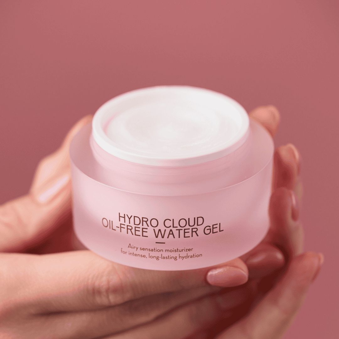 Rosa Tiegel mit weißem Deckel. Aufschrift: HYDRO CLOUD OIL-FREE WATER GEL. Text: Airy sensation moisturizer for intense, long-lasting hydration. Hände halten den Tiegel.