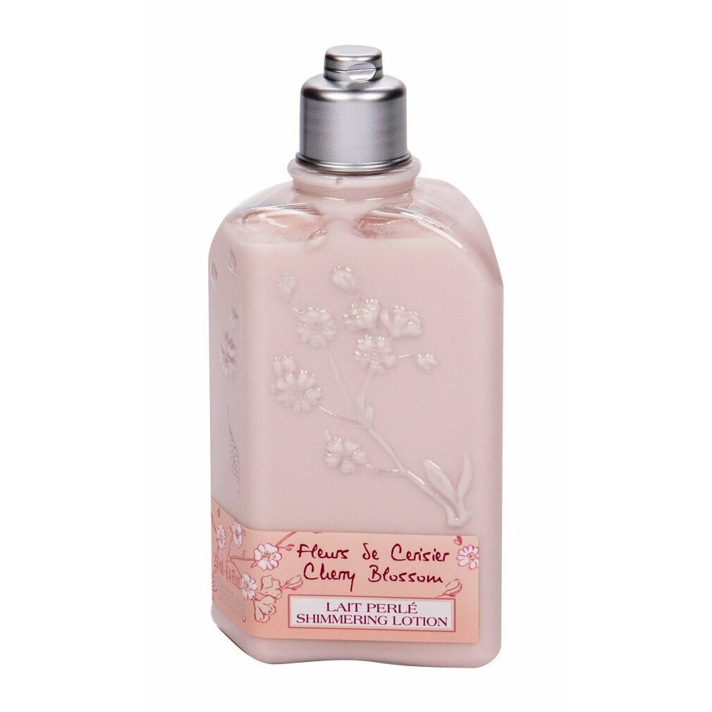Rosa Flasche mit Blütenrelief und silbernem Verschluss. Aufschrift: Fleur de Cerisier Cherry Blossom, Lait Perlé Shimmering Lotion.