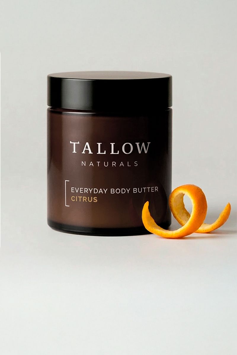 Braune Dose mit schwarzem Deckel. Aufschrift: TALLOW NATURALS, EVERYDAY BODY BUTTER CITRUS. Daneben Orangenschale.