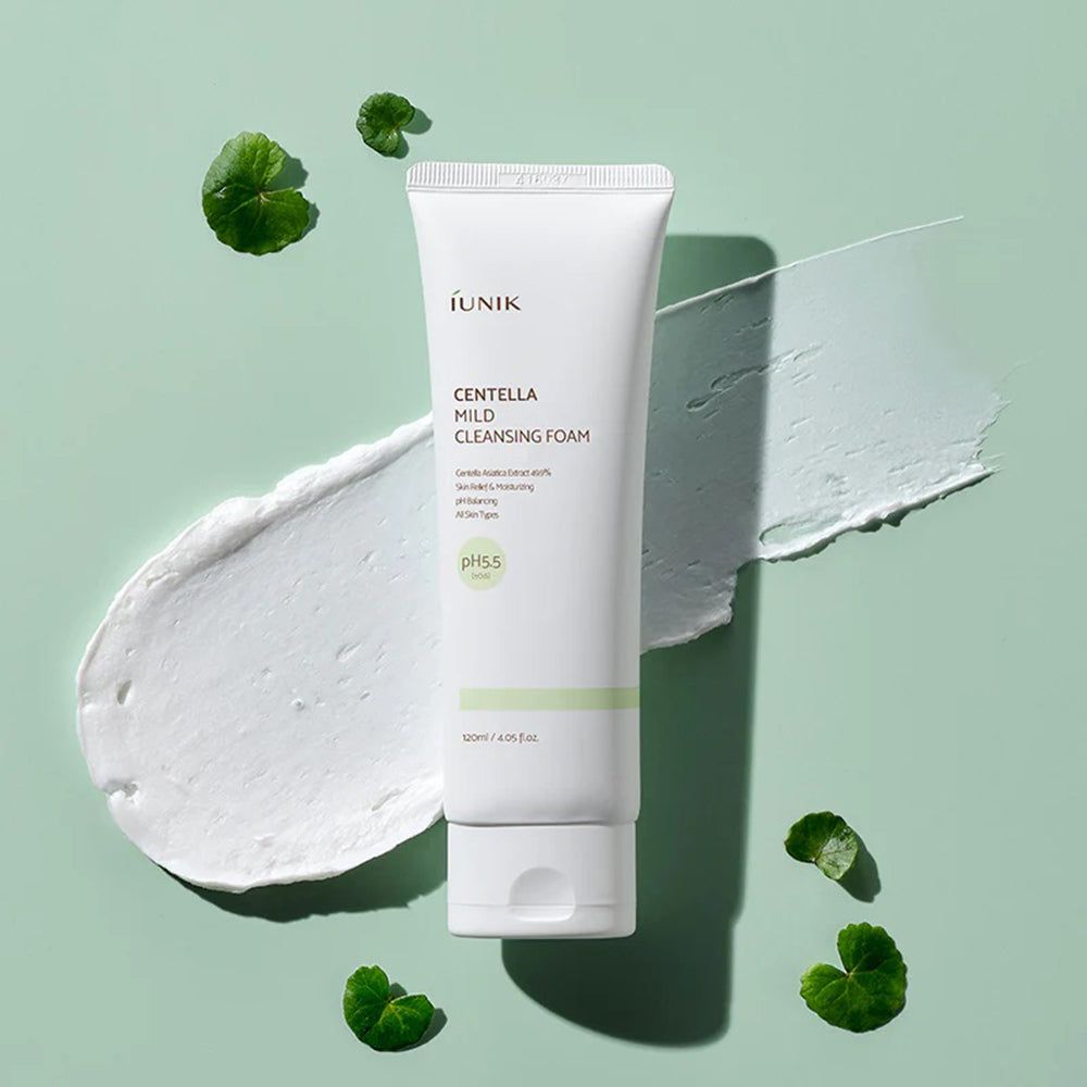 Weiße Tube mit iUNIK Centella Mild Cleansing Foam, pH 5.5, mit grünen Blättern und weißem Schaum.