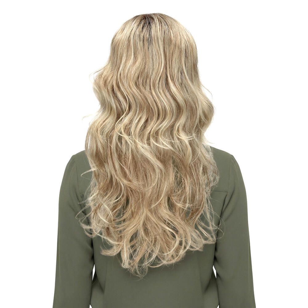 Rückansicht einer blond gewellten Perücke. Die Frau trägt ein grünes Oberteil. Hintergrund weiß.