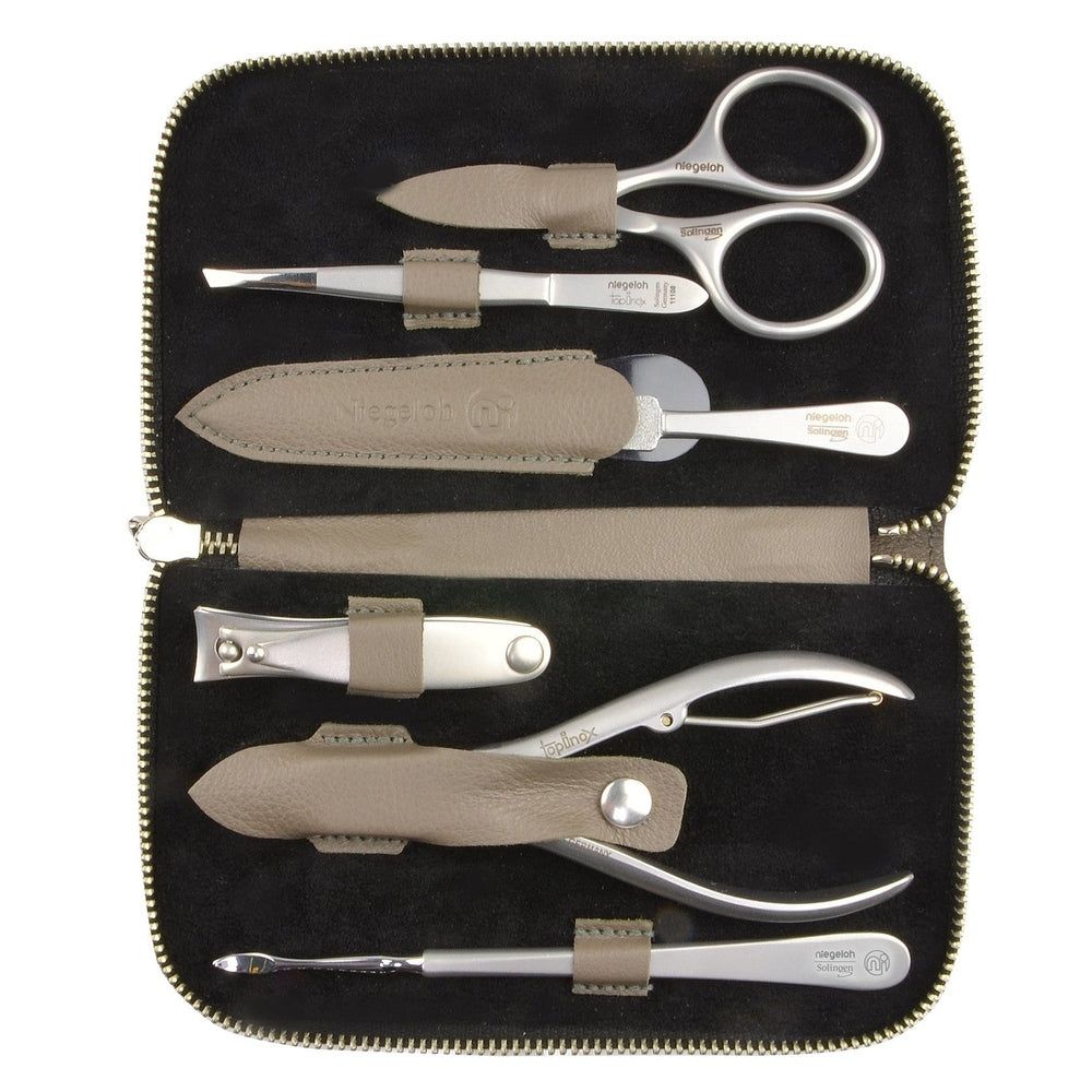 Beige Etui mit Maniküre-Set. Enthält Schere, Pinzette, Nagelfeile, Nagelknipser und weitere Werkzeuge. Schwarzer Innenraum.