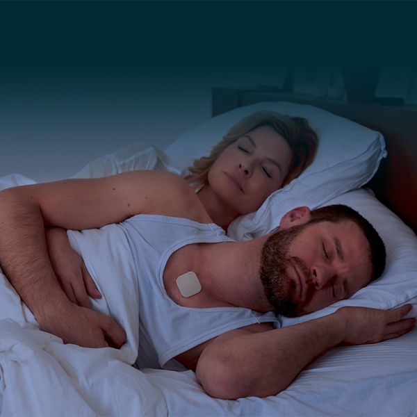 Paar schläft im Bett. Der Mann hat ein quadratisches Pflaster auf der Brust.