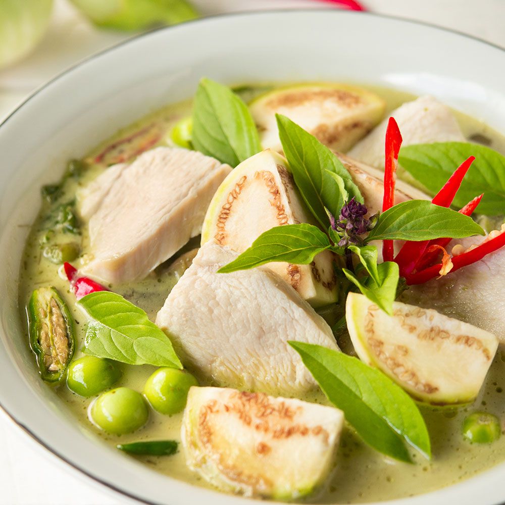 Grüne Curry-Suppe mit Hühnchen, Auberginen, grünen Bohnen und Basilikum. Draufsicht.